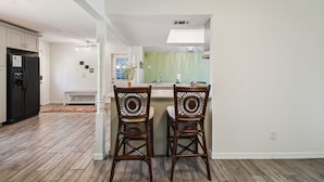 A modern kitchen with a central island, two wooden chairs, and a black refrigerator. - TRANQUILITY. Gated Estate Home. Privacy. (Kissimmee)