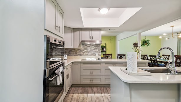 A modern kitchen with a skylight, built-in oven, and a large island with a sink. - TRANQUILITY. Gated Estate Home. Privacy. (Kissimmee)