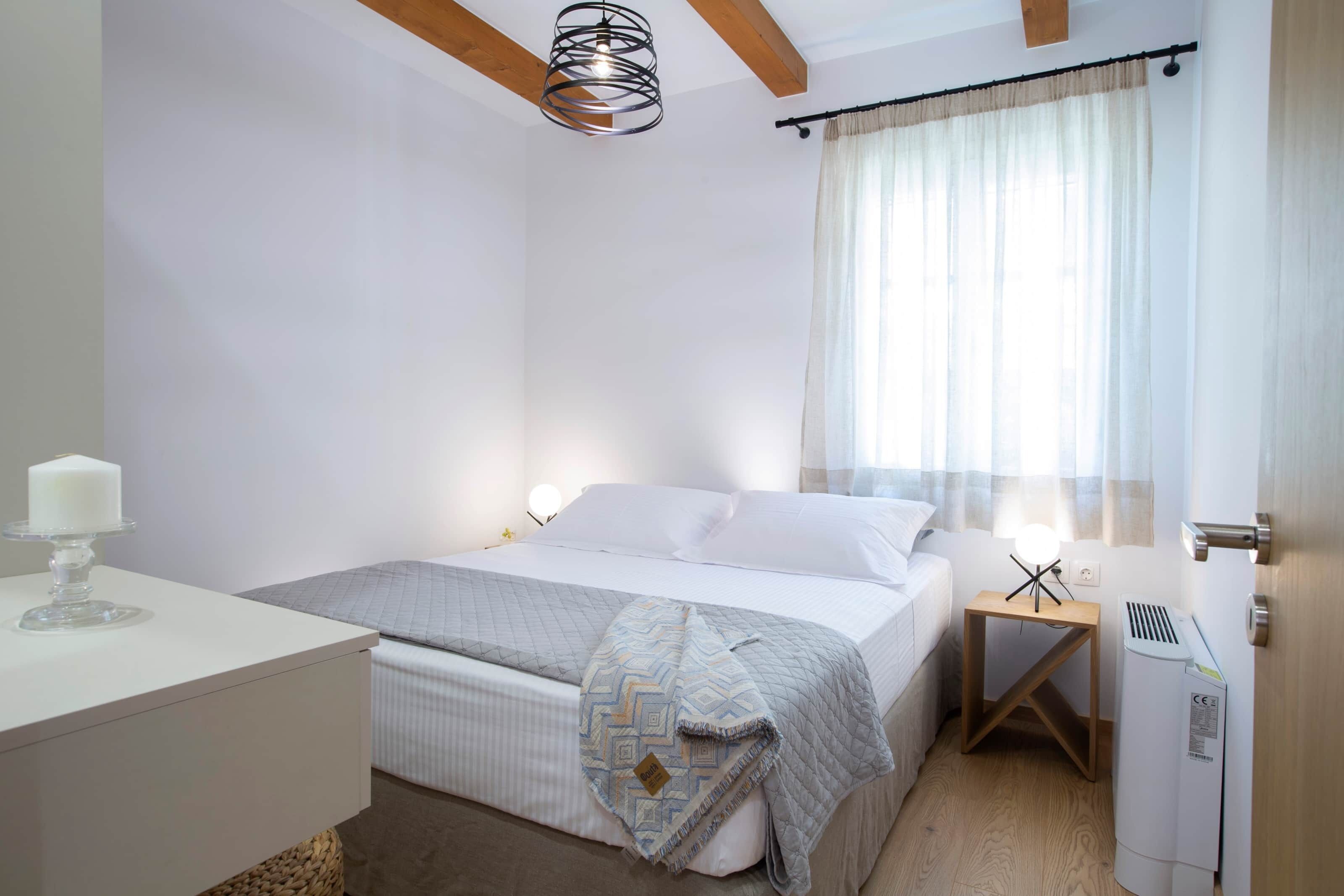 Een slaapkamer met een bed, nachtkastje, lamp en een verwarming.
