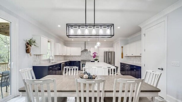 A modern kitchen with white cabinetry, a central island, and a hanging light fixture.