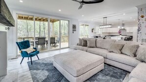 A spacious living room with a large sectional sofa, a blue armchair, and a ceiling fan.