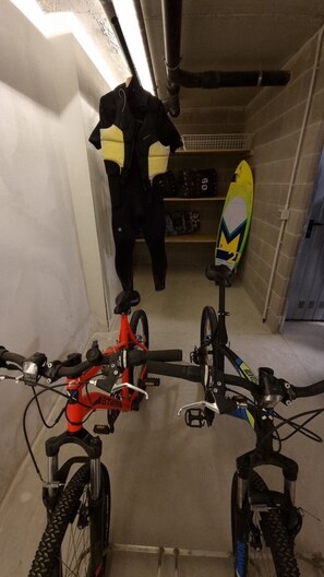 Ein schmaler Innenraum mit zwei Fahrrädern, einem Surfbrett und einer Dame als Deko im Hintergrund.