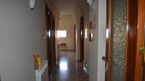 A hallway with a radiator, a wooden door, and a window at the end. - Framamired (Palermo)