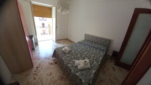 A bedroom with a patterned bedspread, a tufted headboard, and a visible door leading to a balcony. - Framamired (Palermo)