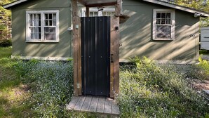 Una casa de una planta con una puerta de madera oscura y un pequeño porche.