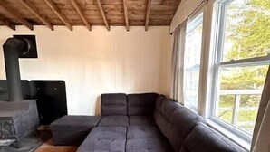 Una sala de estar moderna con un amplio sofá modular, una chimenea empotrada y ventanas grandes que ofrecen vistas al exterior.