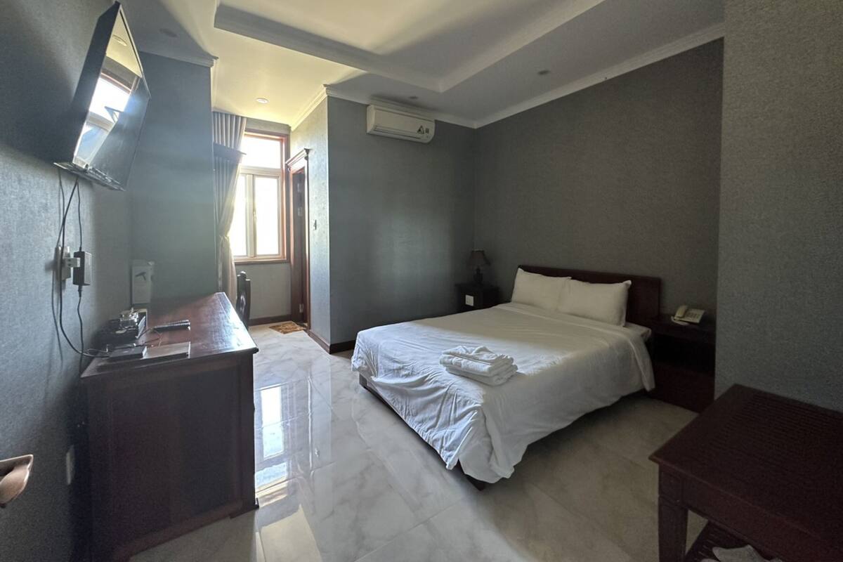Una camera d'albergo con un letto, comodino, scrivania e specchio.