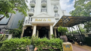Un edifici blanc amb balcons i un rètol que diu "Hotel Le Na".
