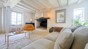 Una sala de estar con chimenea, sofá, mesa de centro y una silla.