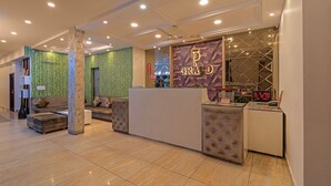 A reception area with a modern design, featuring a reception desk, a seating area with a sofa and armchairs, and a decorative wall with geometric patterns. - Itsy Hotels P Grand (Ludhiana)
