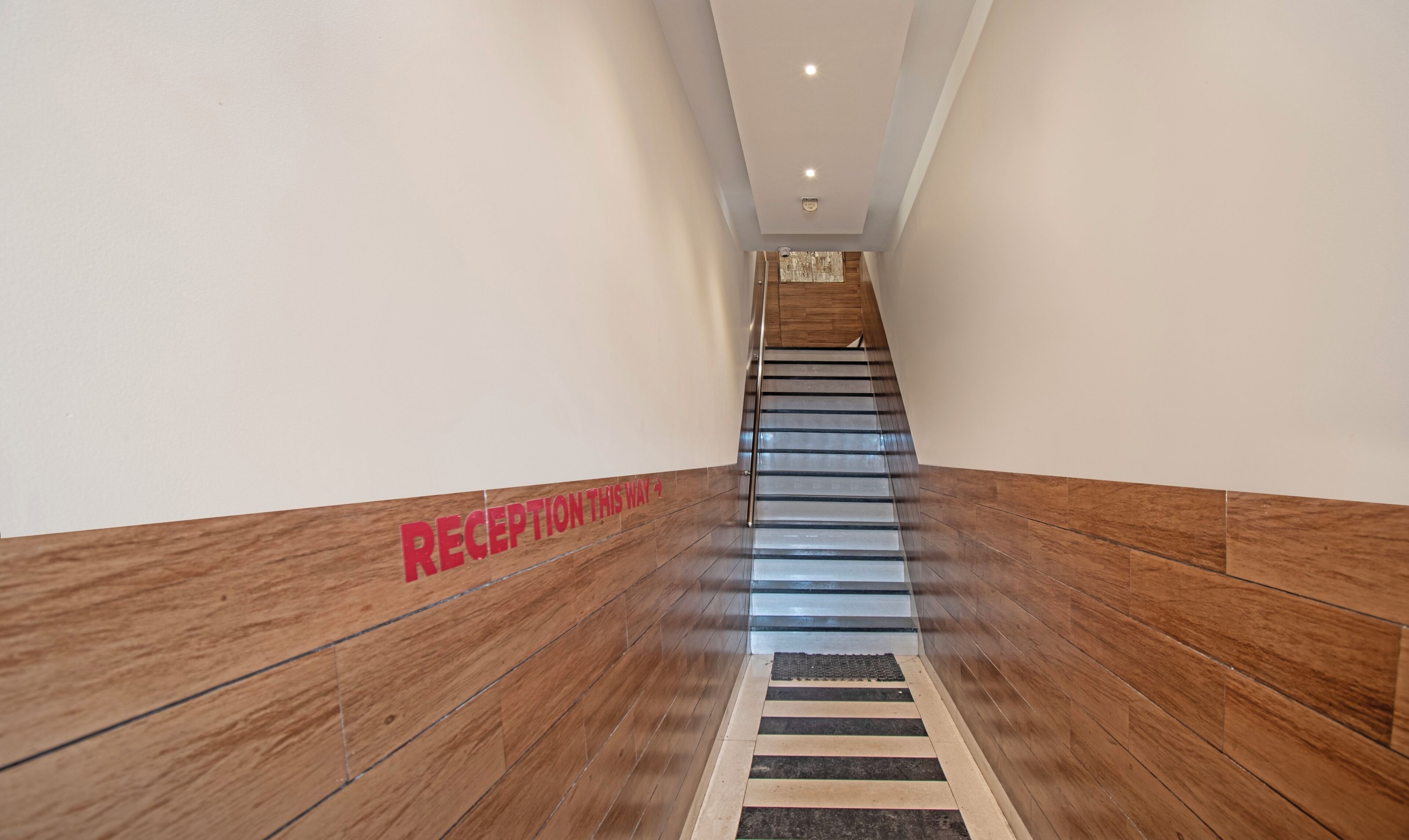 A modern reception area with a wooden floor and a sign indicating the reception is on this way.