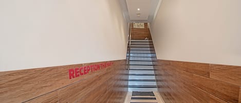 A modern reception area with a wooden floor and a sign indicating the reception is on this way.