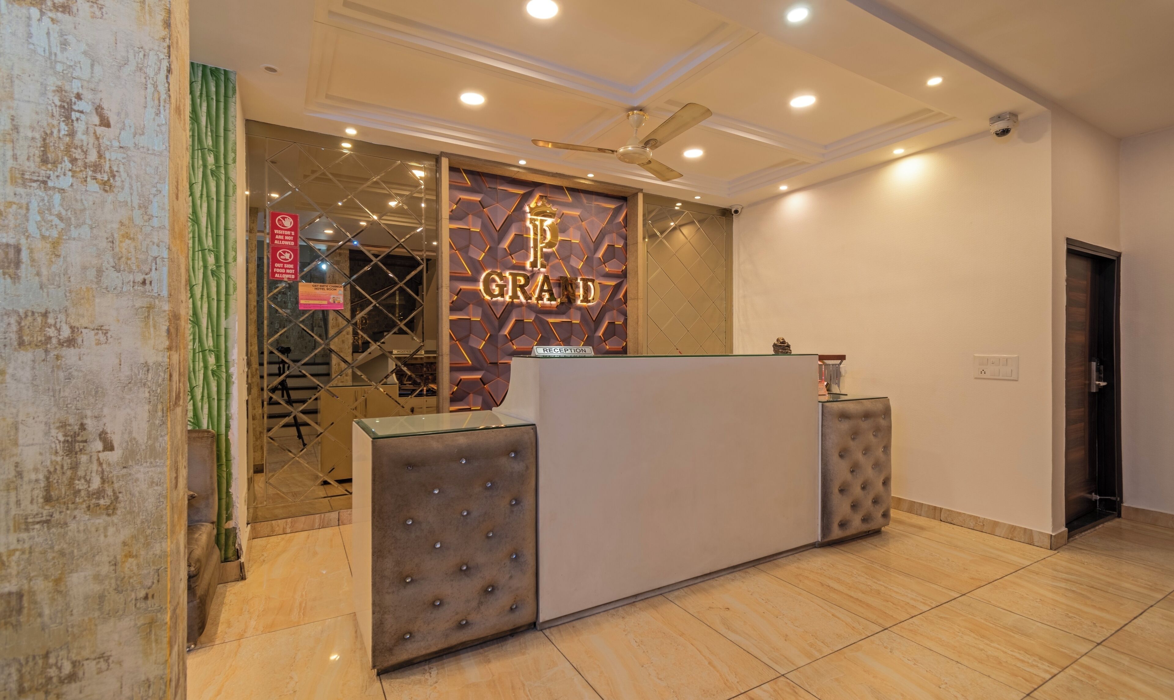 A reception area with a modern design, including a reception desk, a ceiling fan, and a sign indicating a hotel room.