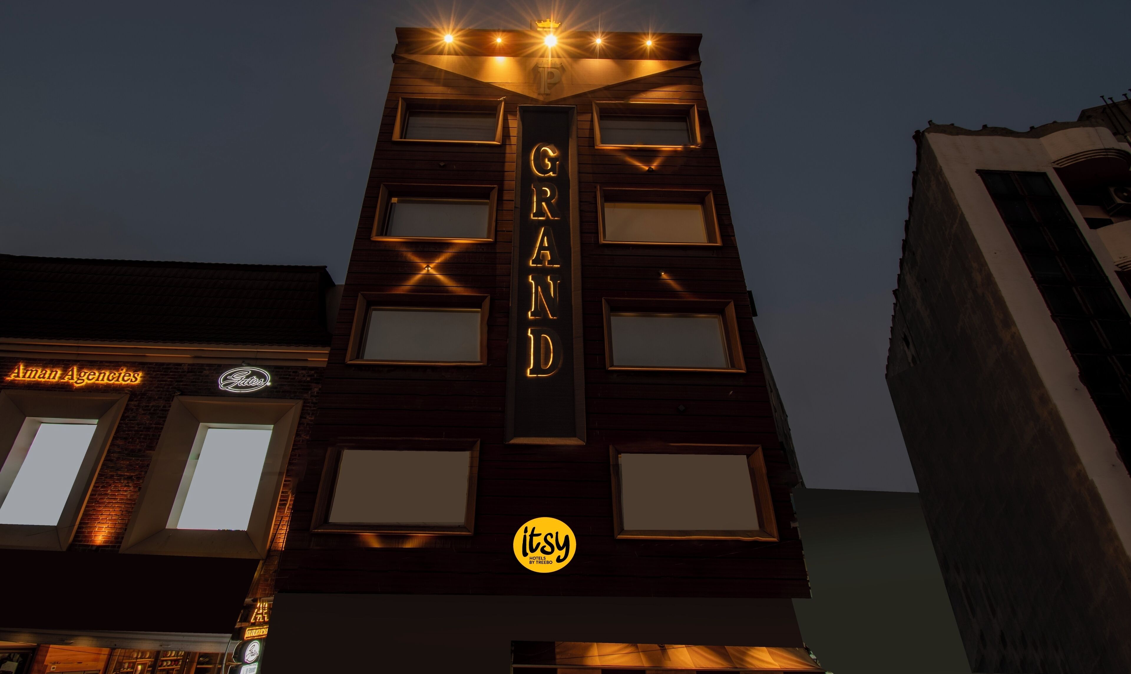 Ein Gebäude mit einem auffälligen 'GRAND'-Schild an der Fassade, mit zahlreichen Fenstern und einem Logo unten.