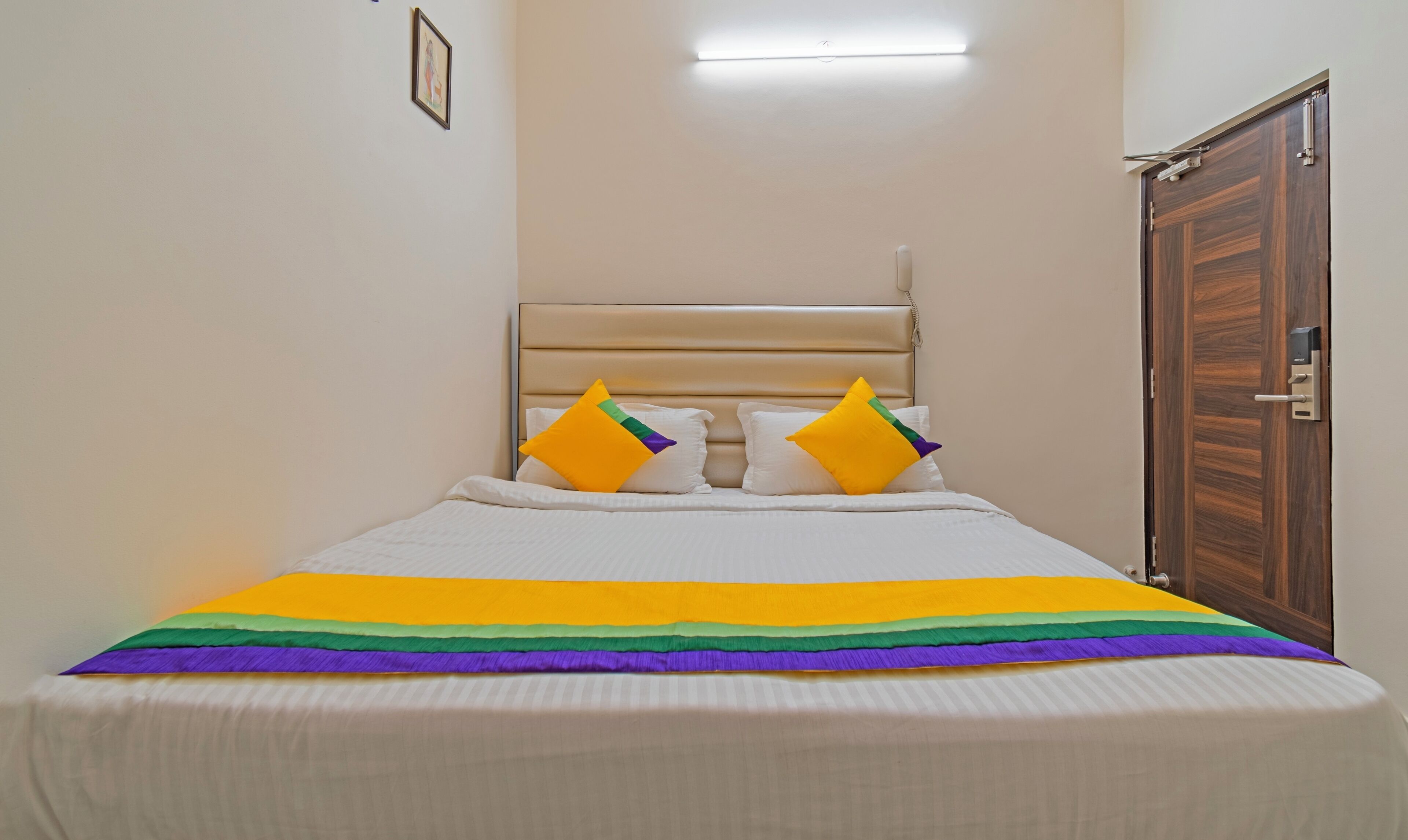 Ein Bett mit bunte Bettdecke, einem Holz-Kopfteil und einer Tür mit Griff.