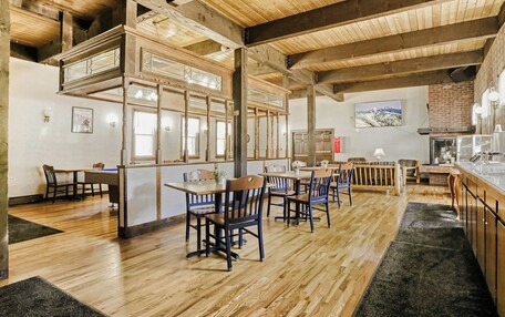 A restaurant with wooden floors, high ceilings, and a bar area.