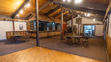 A rustic interior with wooden beams, a bar area, and multiple seating arrangements.