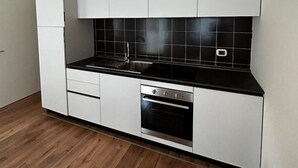 A compact kitchen with white cabinets, a black countertop, and a wooden floor. - DV Garda Suite 55.0 (Campione del garda)