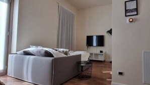 A bedroom with a bed, a TV, a small table, and a cabinet. - DV Garda Suite 55.0 (Campione del garda)