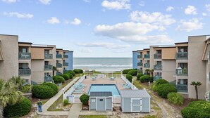 Et strandhotel med pool, liggestole og havudsigt.