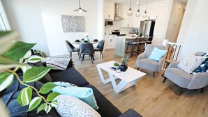 Un salon moderne comprenant un canapé, deux fauteuils, une table basse et un coin repas avec une table et des chaises.