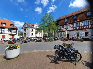 A cobblestone street with outdoor seating areas, bicycles, and traditional half-timbered buildings. - 1-Bedroom Apartment in Lorsch (Lorsch)