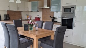 Eine moderne Küche mit weißen Schränken, einem Holzespeiseplatz mit vier Stühlen und einem eingebauten Backofen.