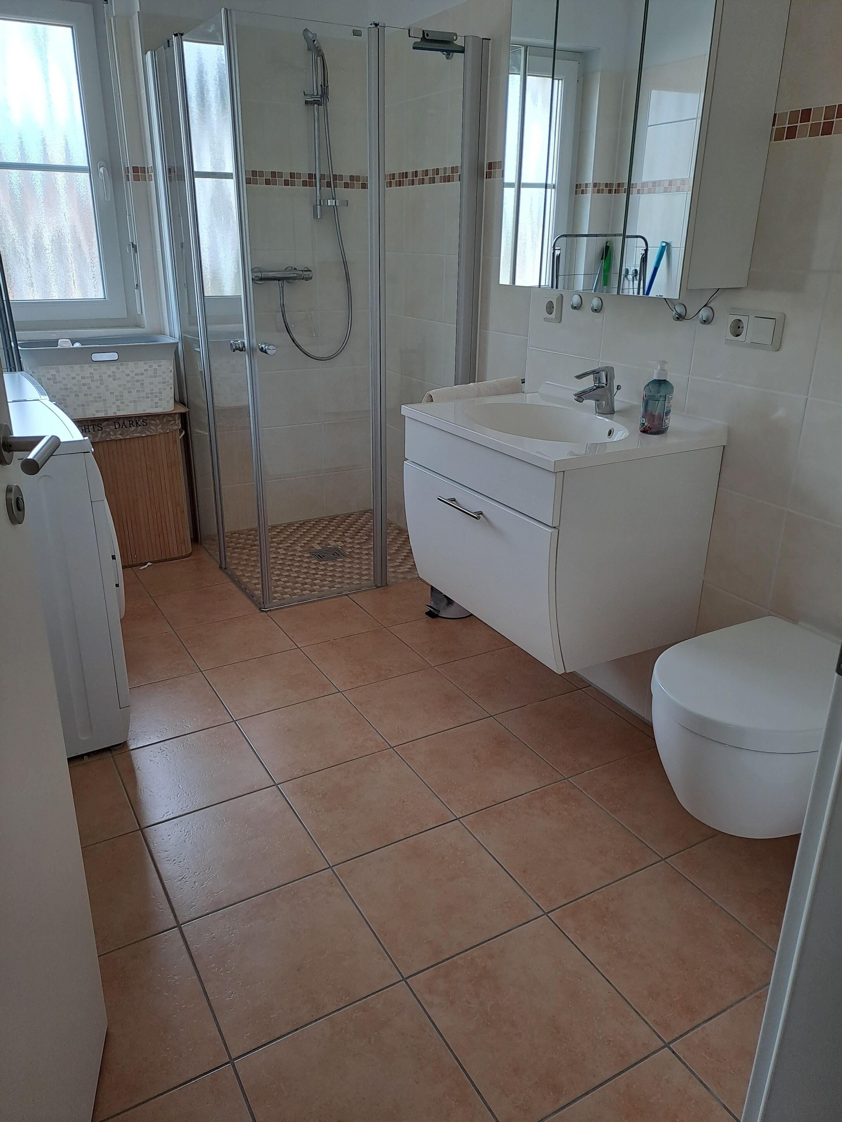 A bathroom with a glass-enclosed shower, a sink with a mirror, and a toilet.