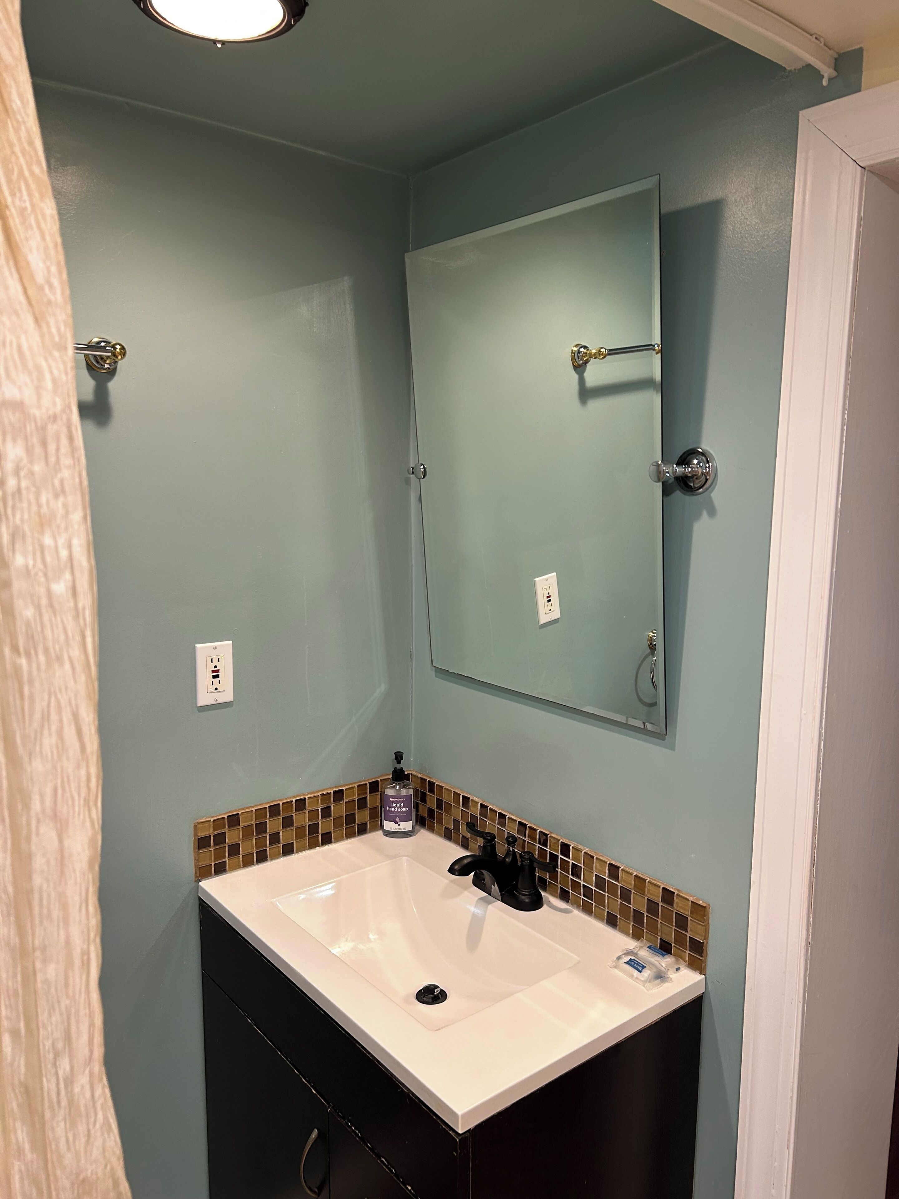 A bathroom with a white sink, a mirror, and a tiled backsplash.