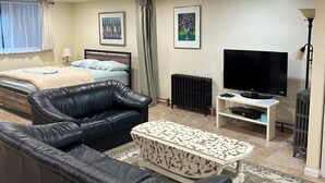A living room with a sofa, a coffee table, a TV, and a radiator. - Entire basement apartment - 2067 Park Road, Nw Dc. (Washington)