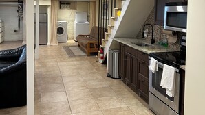 A modern kitchen with a built-in oven, stainless steel appliances, and a small dining area with a sofa. - Entire basement apartment - 2067 Park Road, Nw Dc. (Washington)