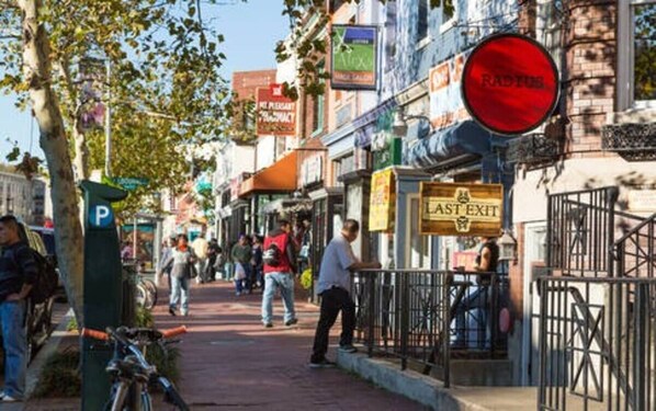 A busy street with pedestrians, a red traffic light, and various storefronts.