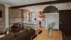 Une cuisine moderne avec un mur en pierre, des poutres en bois et un grand îlot central.