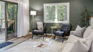 A living room with a glass door leading to a balcony, a sofa, two armchairs, a small side table, and a floor lamp. - Spacious townhome within steps of Apple Valley Golf Course--Indoor pool! (lake lure)