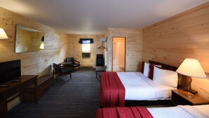 A wooden cabin room with a bed, a desk, a chair, a TV, and a mirror.