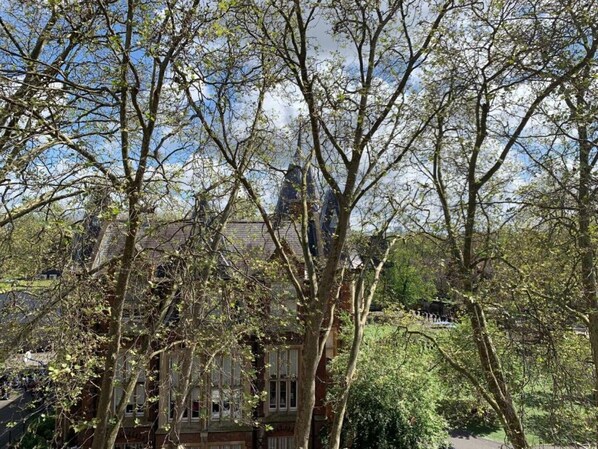 A view of a building with multiple windows and a brick facade, surrounded by trees.