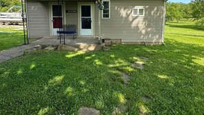 A small, single-story building with a metal roof, a front door, and a small porch area. - Quiet Cottage in the heart of Burr Oak State Park. (Glouster)