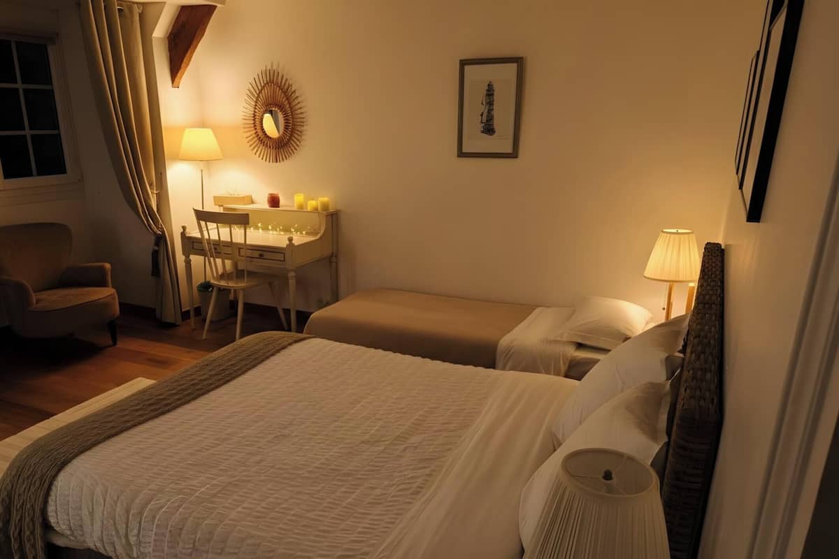 A hotel room with a bed, a desk, a chair, a lamp, and a picture on the wall.