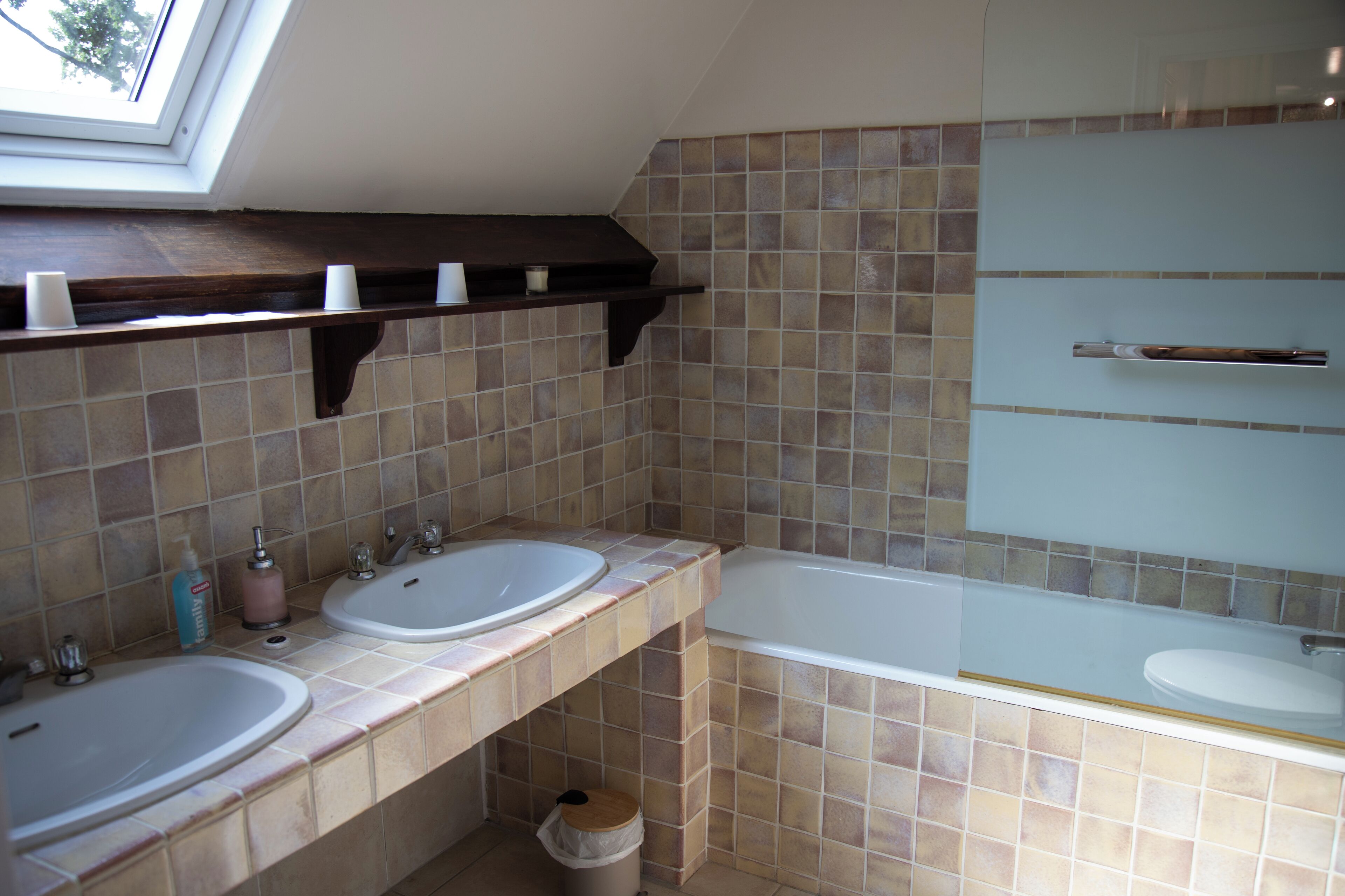 Une salle de bain avec deux lavabos, une baignoire et une fenêtre de toit.