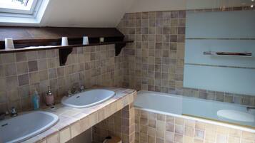 Une salle de bain avec deux lavabos, une baignoire et une fenêtre de toit.