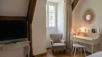 Une chambre avec une télévision, un bureau, une chaise, un lit et une fenêtre avec des rideaux.