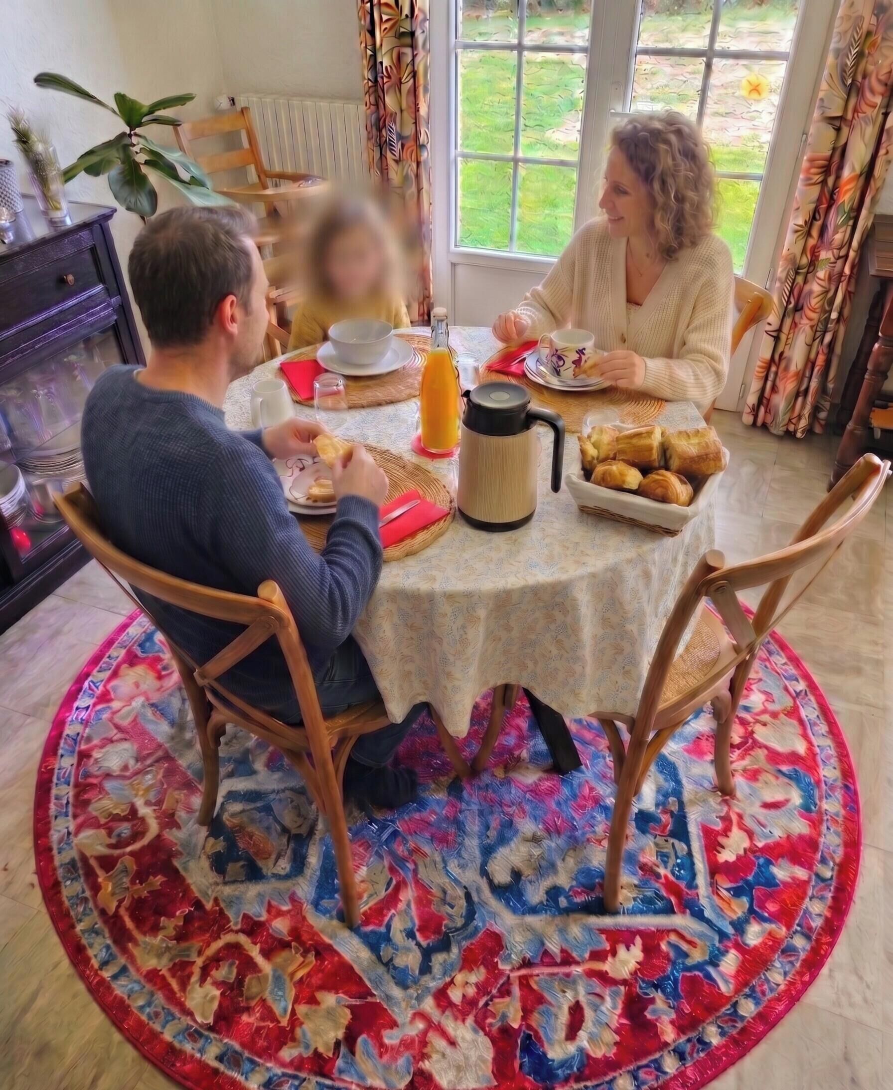 Ein Essbereich mit einem runden Tisch, Stühlen, einem gemusterten Teppich und Blick ins Freie.