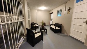 A narrow hallway with two black chairs and a small table, a white door on the right, and a barred gate on the left. - Puerto Rico: 5-Minute Airport / Parking / Carolina, San Juan. (Carolina)