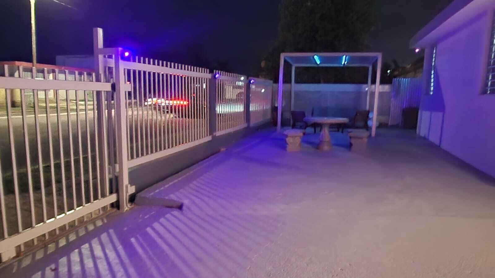 A gated outdoor area with a covered seating area and a pathway leading to a building.