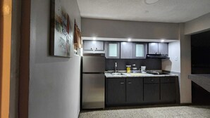 A modern kitchen with dark cabinets, stainless steel appliances, and a countertop with various items. - Puerto Rico: 5-Minute Airport / Parking / Carolina, San Juan. (Carolina)