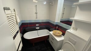 Et lille badeværelse med badekar, toilet og håndvask.