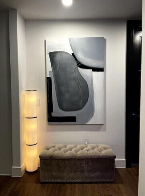 Relax in a serene space with a large abstract painting, tufted bench, and warm ambient lighting.