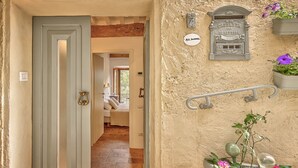 A hallway with a door leading to a bedroom, a mailbox, and a potted plant with flowers. - Appartamenti Anguria Toscana One-bedroom (Sinalunga)