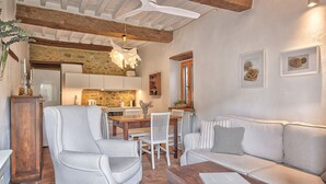 A cozy living area with a sofa, armchair, and dining table. - Appartamenti Anguria Toscana One-bedroom (Sinalunga)