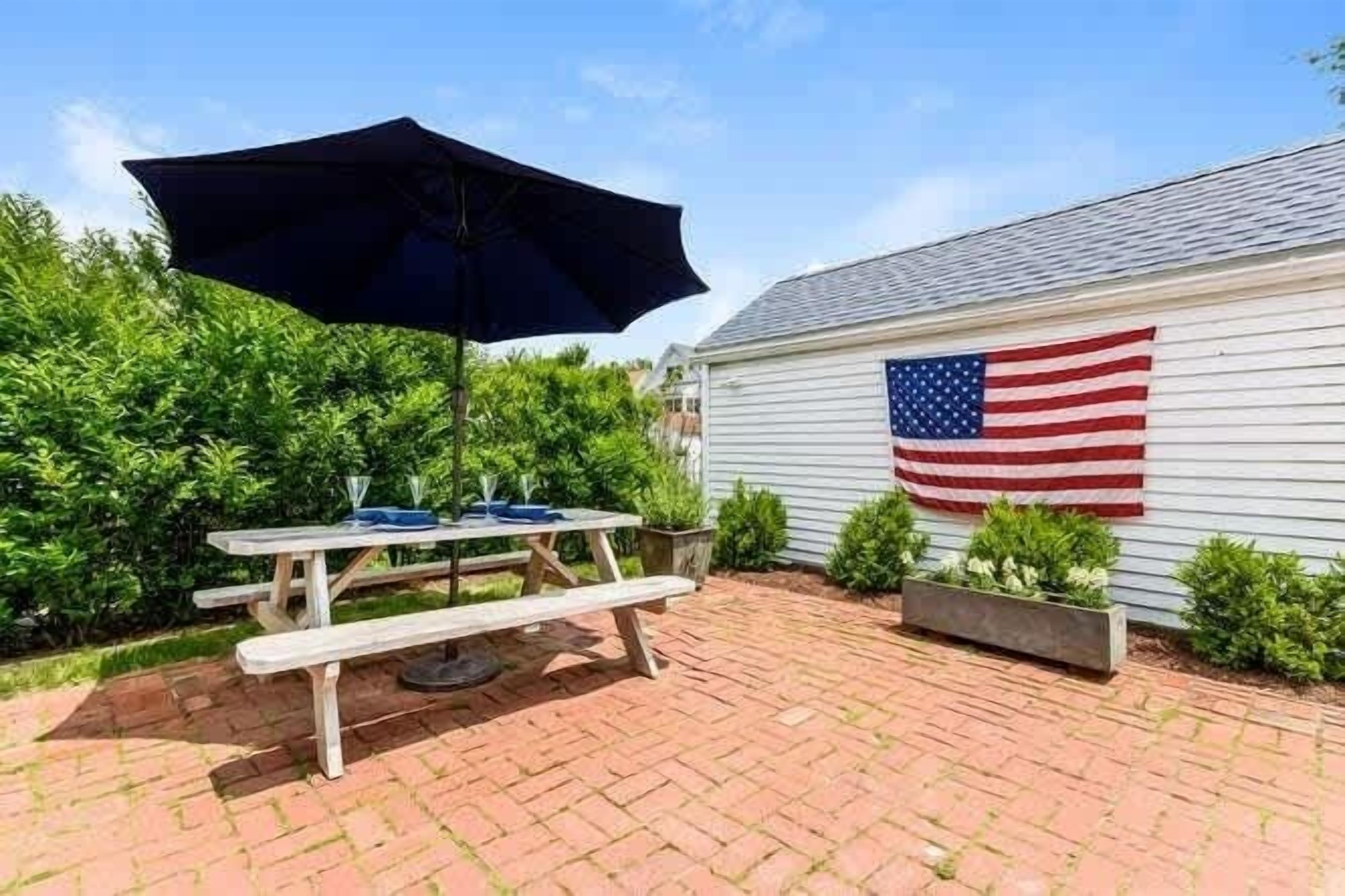 Uma mesa de piquenique com uma bandeira americana, rodeada por vegetação.